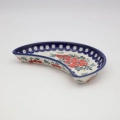 Hand-painted Bolesławiec stoneware crescent dish with iconic blue and white folk art motifs.