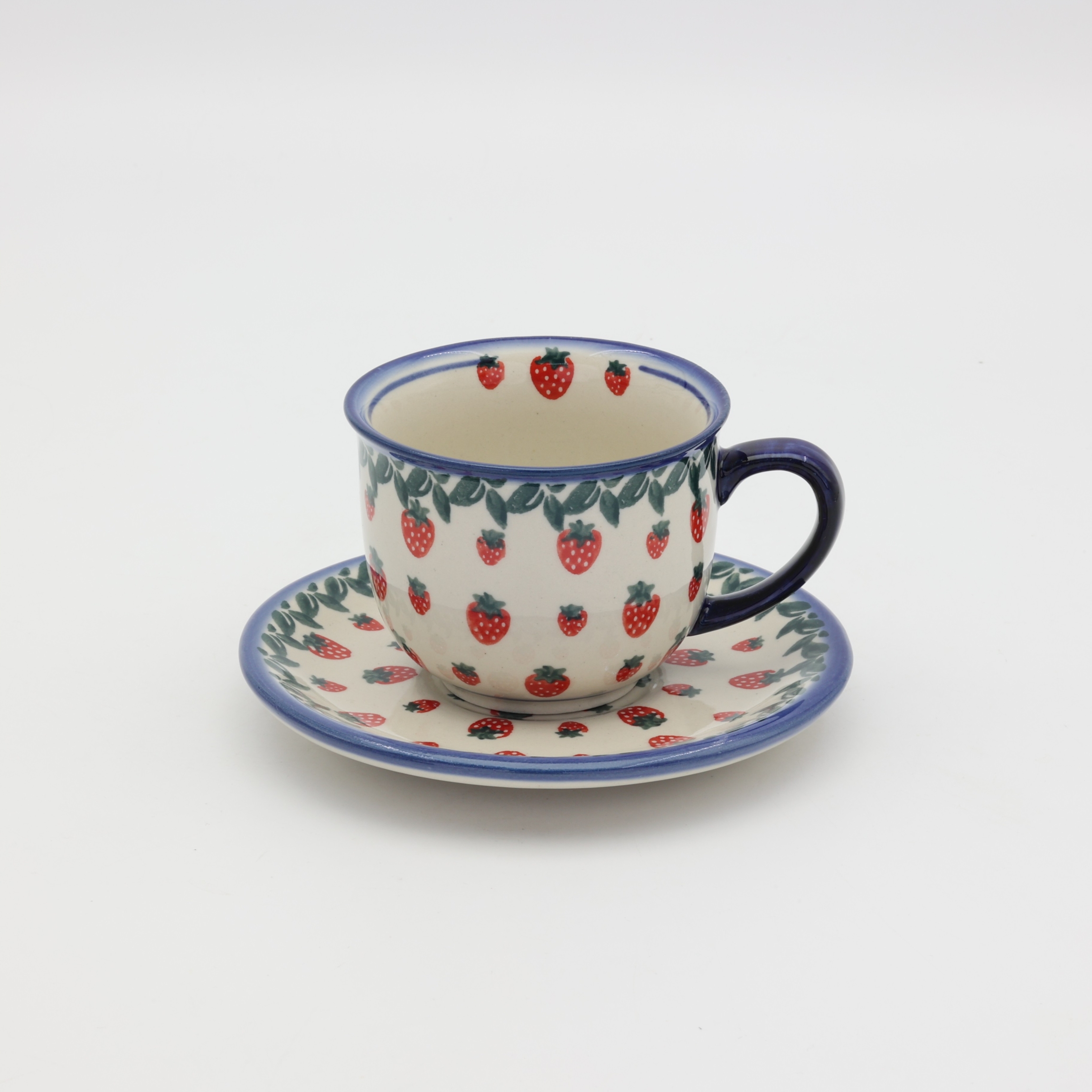 Hand-painted Bolesławiec cup and saucer decorated with a charming strawberry pattern. Traditional Polish pottery perfect for coffee, tea, and kitchen decor.